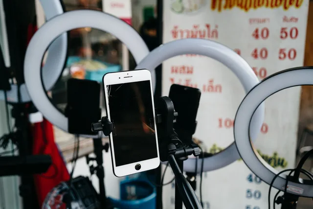A modern smartphone mounted on a tripod surrounded by ring lights, ideal for vlogging or content creation. UGC Creator Platforms and Channels: Where to Take Brand Deals