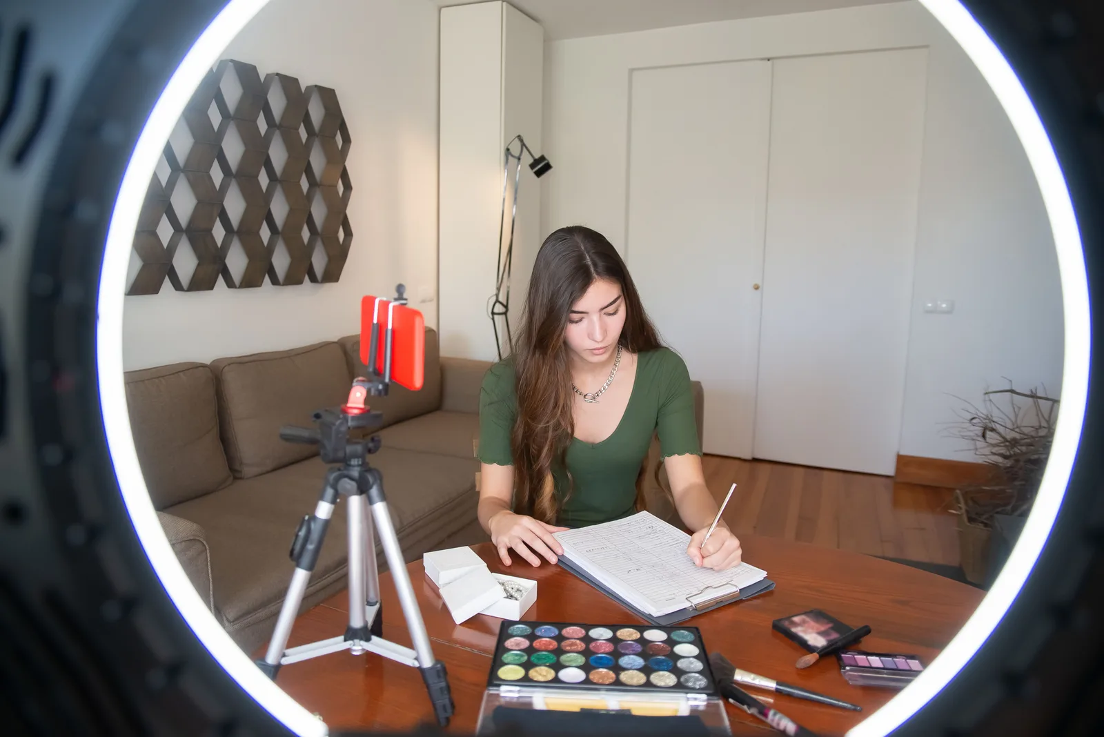 A young woman writing notes and creating video content at her desk with a ring light. How long until a UGC creator business breaks even, and at what margin