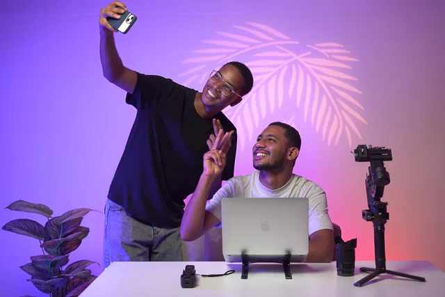 Two young adults taking a selfie in a modern studio with vibrant lighting and tech equipment. UGC creator sponsorship contract: the risk clauses to review